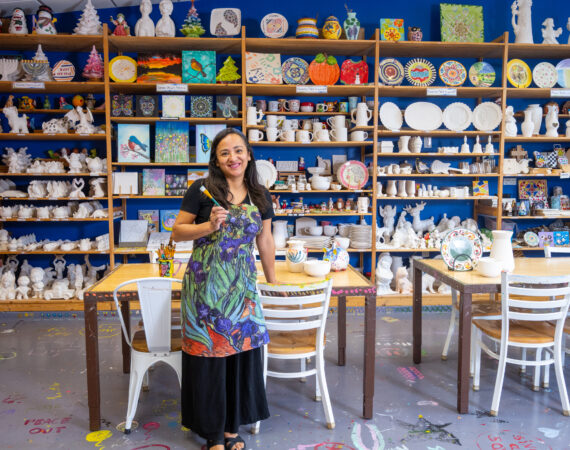 Store owner holding a paint brush inside neighborhood store